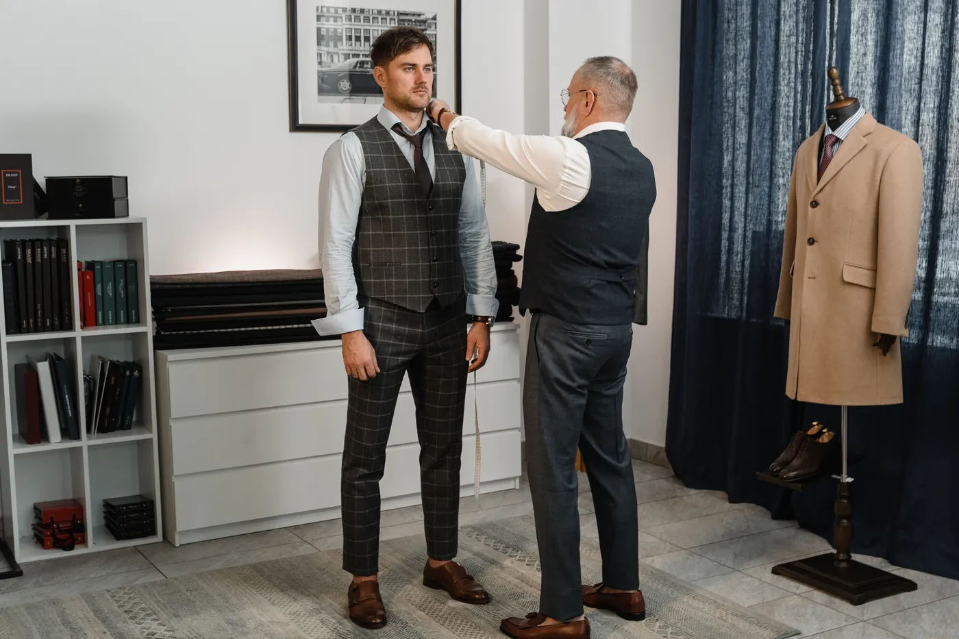 Tailor checking a male client’s shoulder fit in an atelier